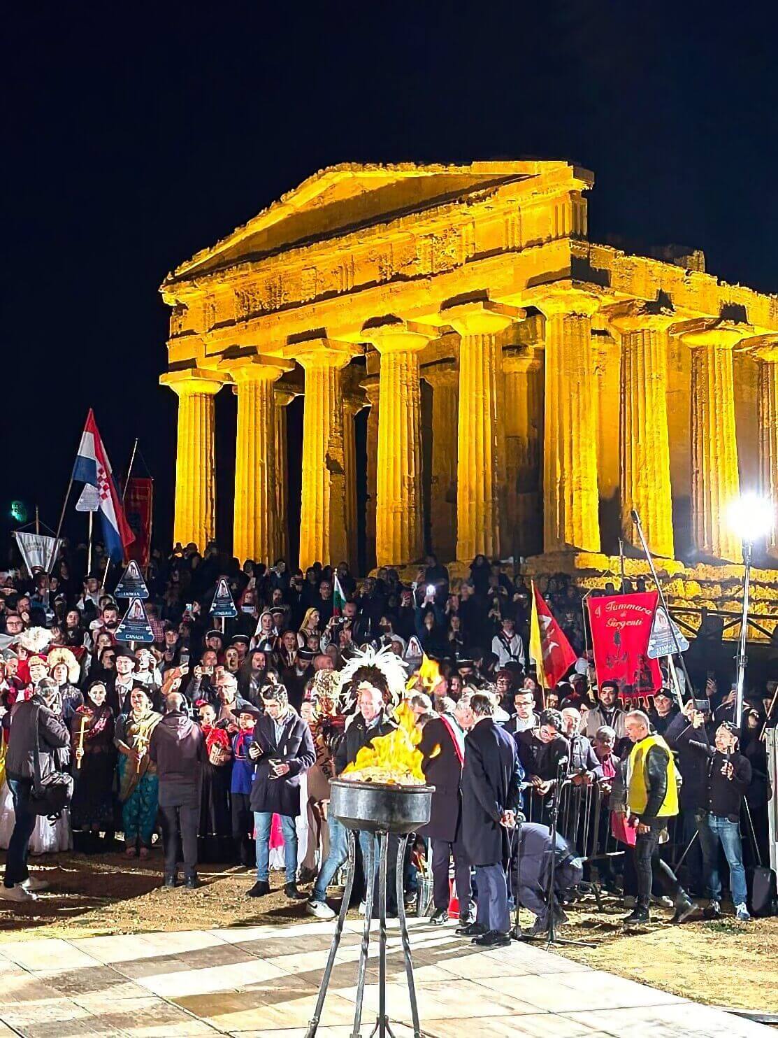 accensione-tripode-pace-inaugurazione-giardino-della-pace-agrigento Cerimonia di accensione del tripode della pace durante l'inaugurazione del Giardino della Pace ad Agrigento, davanti al Tempio della Concordia illuminato, con una folla di spettatori in festa durante il Mandorlo in Fiore.